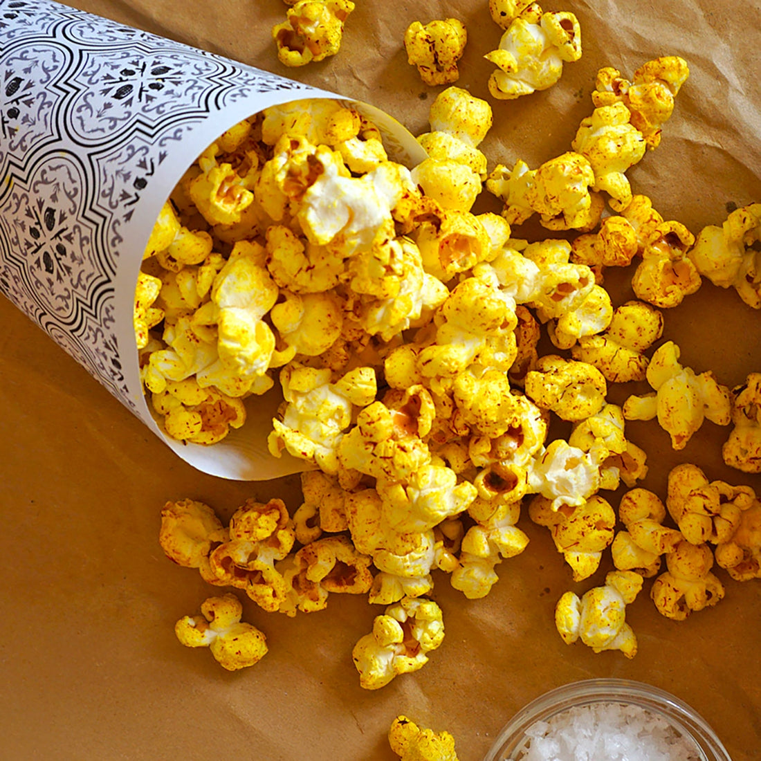 Eine Tüte gefüllt safranfarbenen Popcorn und eine Schale Flor de Sal