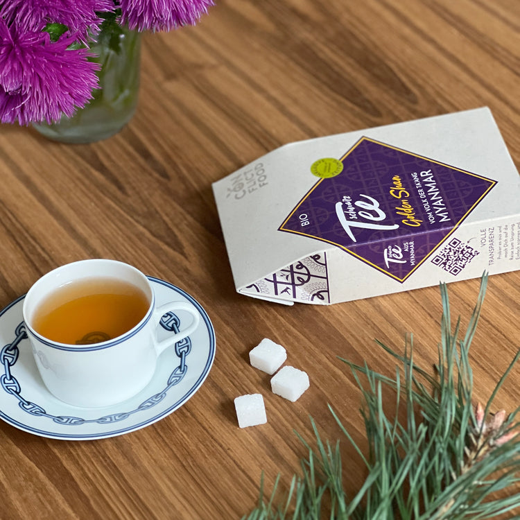 Eine Tasse Tee und ein Päckchen Schwarztee Golden Shan von Conflictfood
