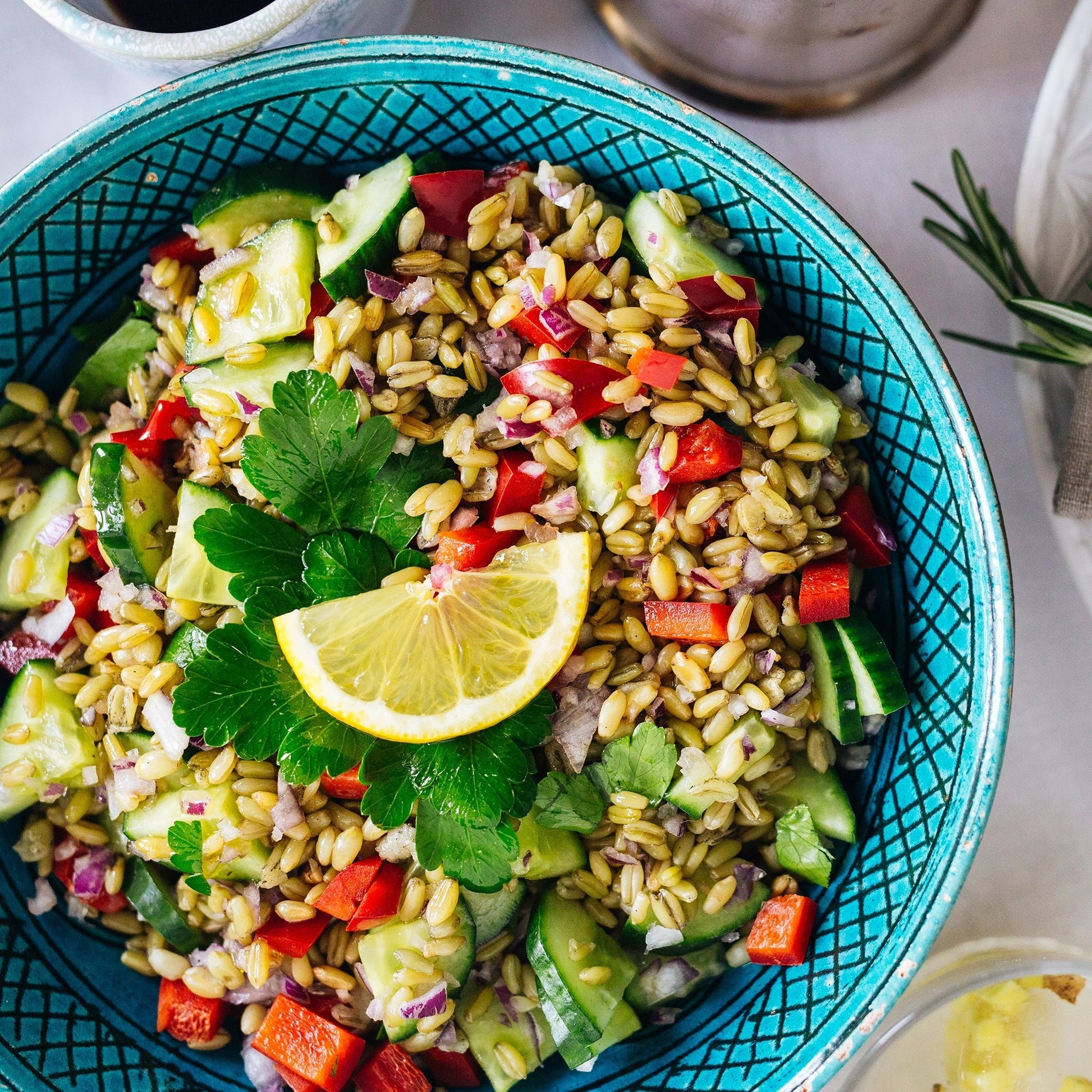 Freekeh Salat in einer blauen Schüssel mit Zitrone und Petersilie als Dekoration