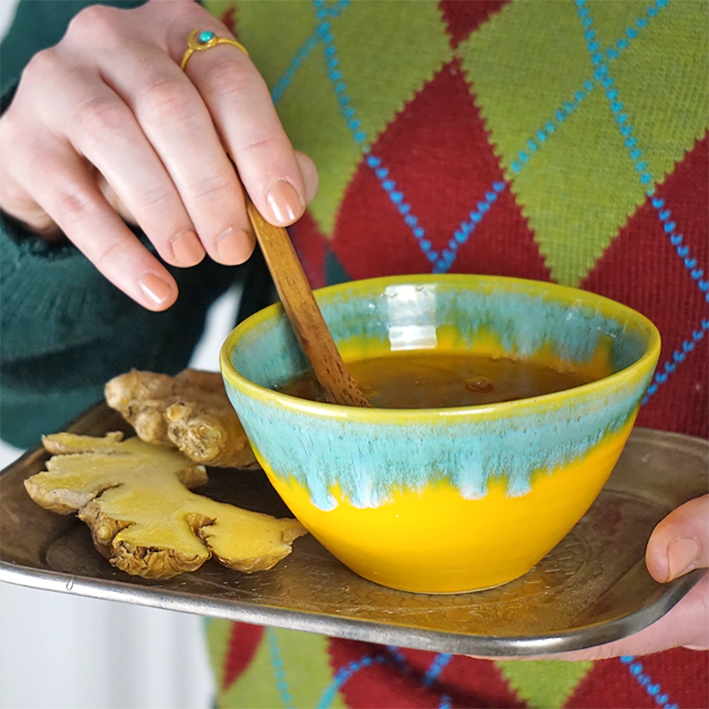 Eine Tasse Tee mit Löffel und ein Stück frischer Ingwer