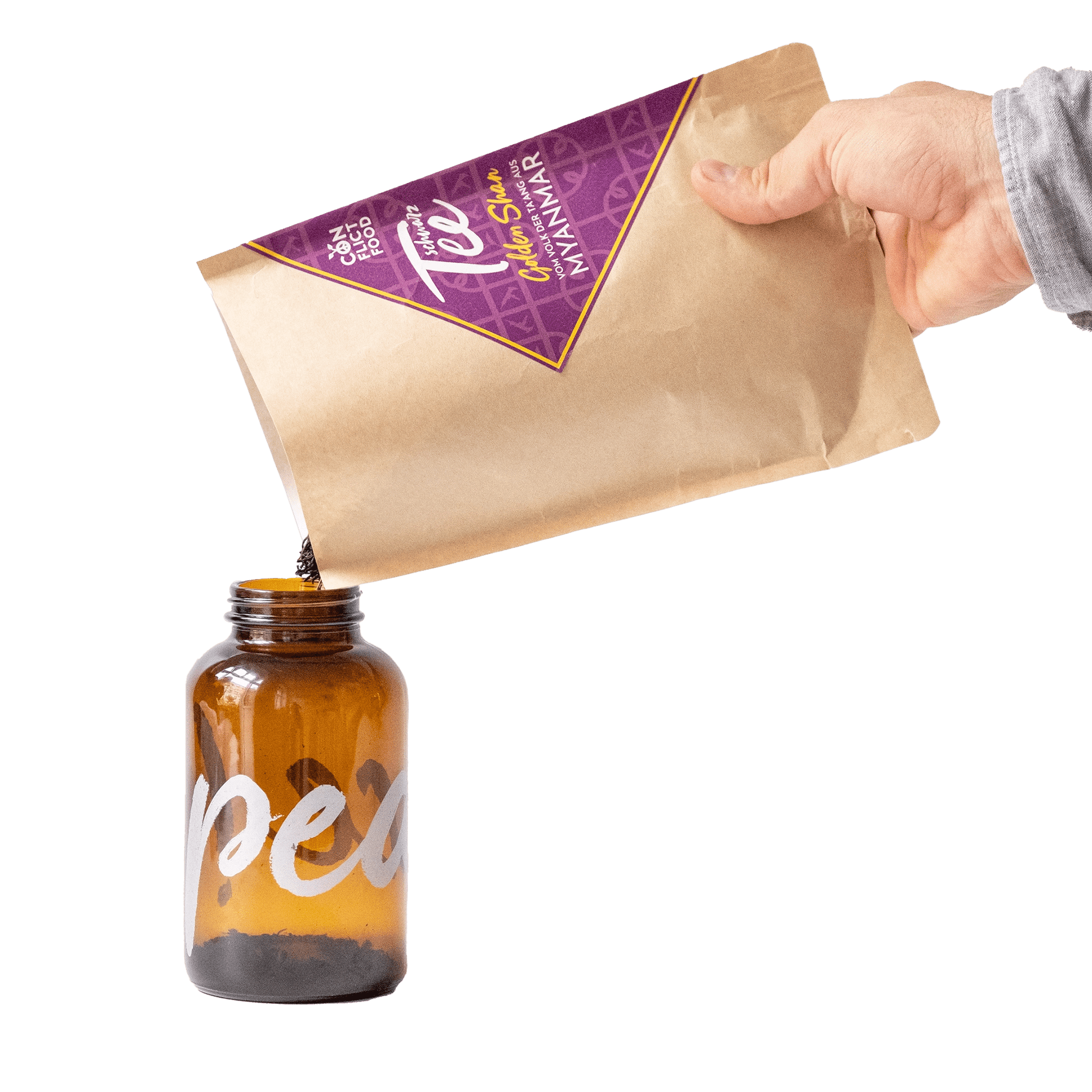 Hand hält Conflictfood-Vorratsbeutel Schwarztee Golden Shan aus Myanmar und schüttet Tee in braunes Vorratsglas und weisser Typo PEACE