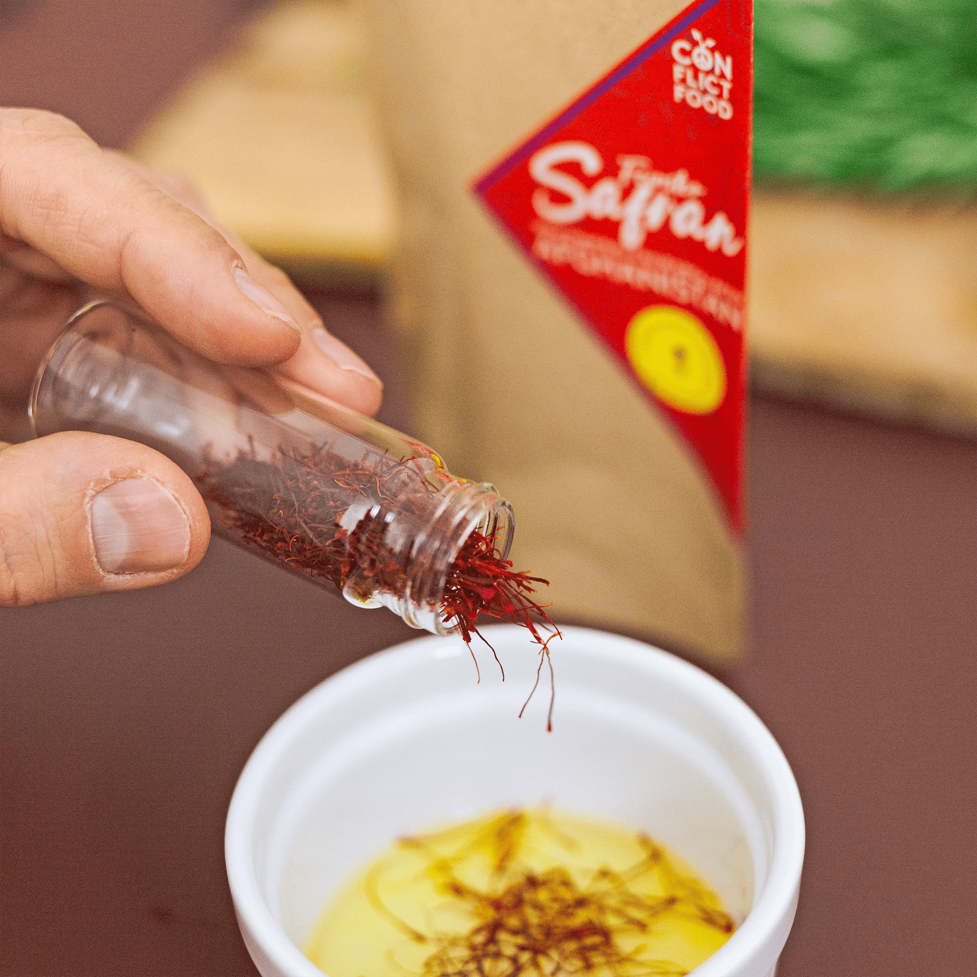 Rote Safranfäden werden in eine Tasse mit Wasser geschüttet