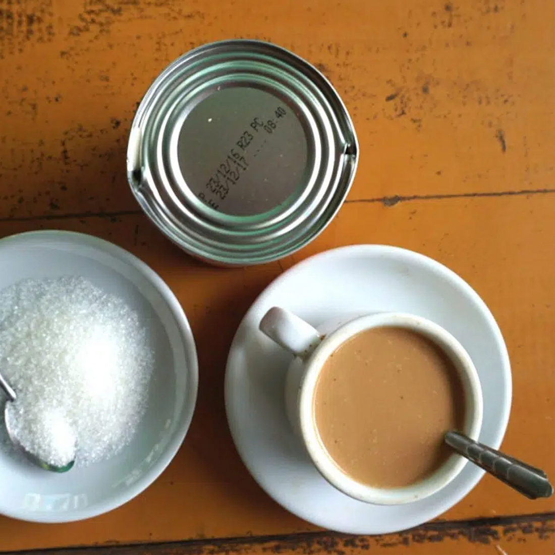 Eine Tasse Burmesischer Milchtee mit einer Dose Kondensmilch und einer Schale Zucker