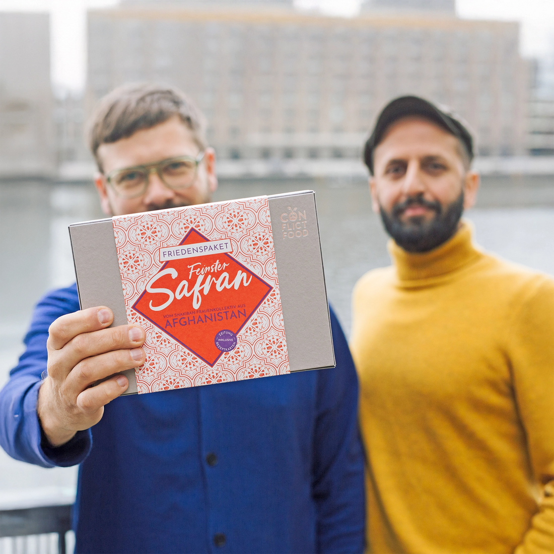 Gernot Würtenberger und Salem El-Mogaddedi von Conflictfood halten ein Geschenkpaket mit feinstem Safran aus Afghanistan in der hand