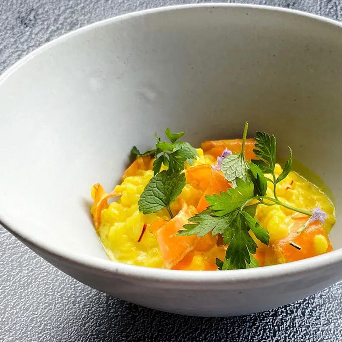 Eine Schale mit gelbem Risotto und feinem Gemüsedekor