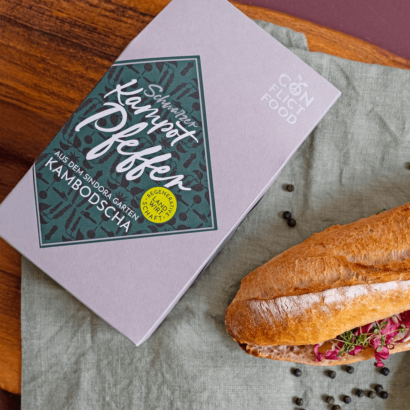 Ein Päckchen schwarzer Kampot Pfeffer von Conflictfood und ein Sandwich